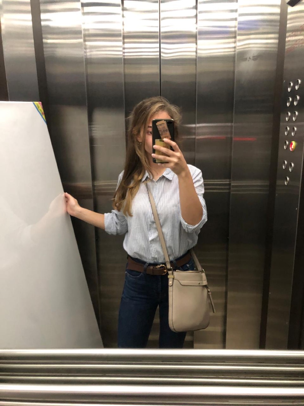 Elevator mirror selfie holding a large blank canvas