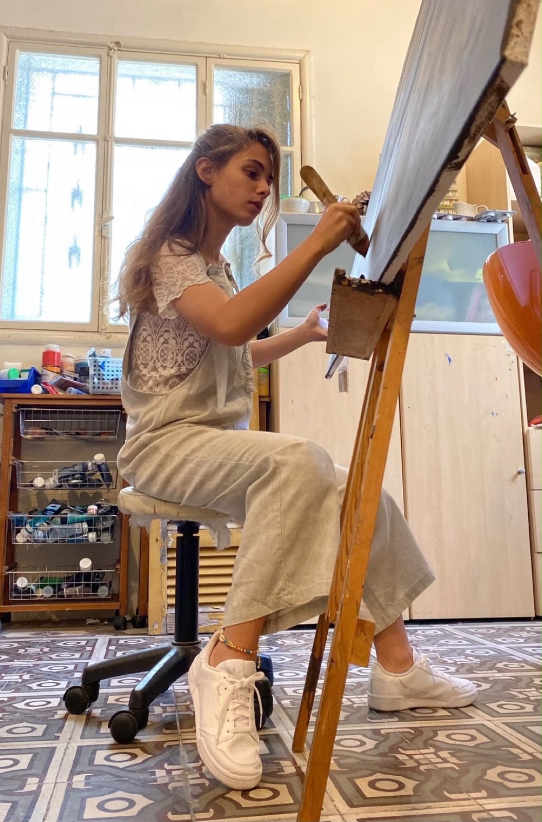 Myriam painting at an easel in her studio